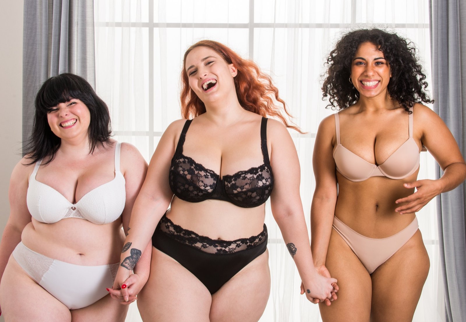 Drie lachende vrouwen in lingerie in een lichte ruimte